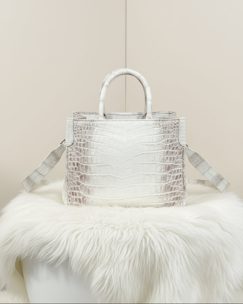 White textured handbag on a white fur surface with a light gray background