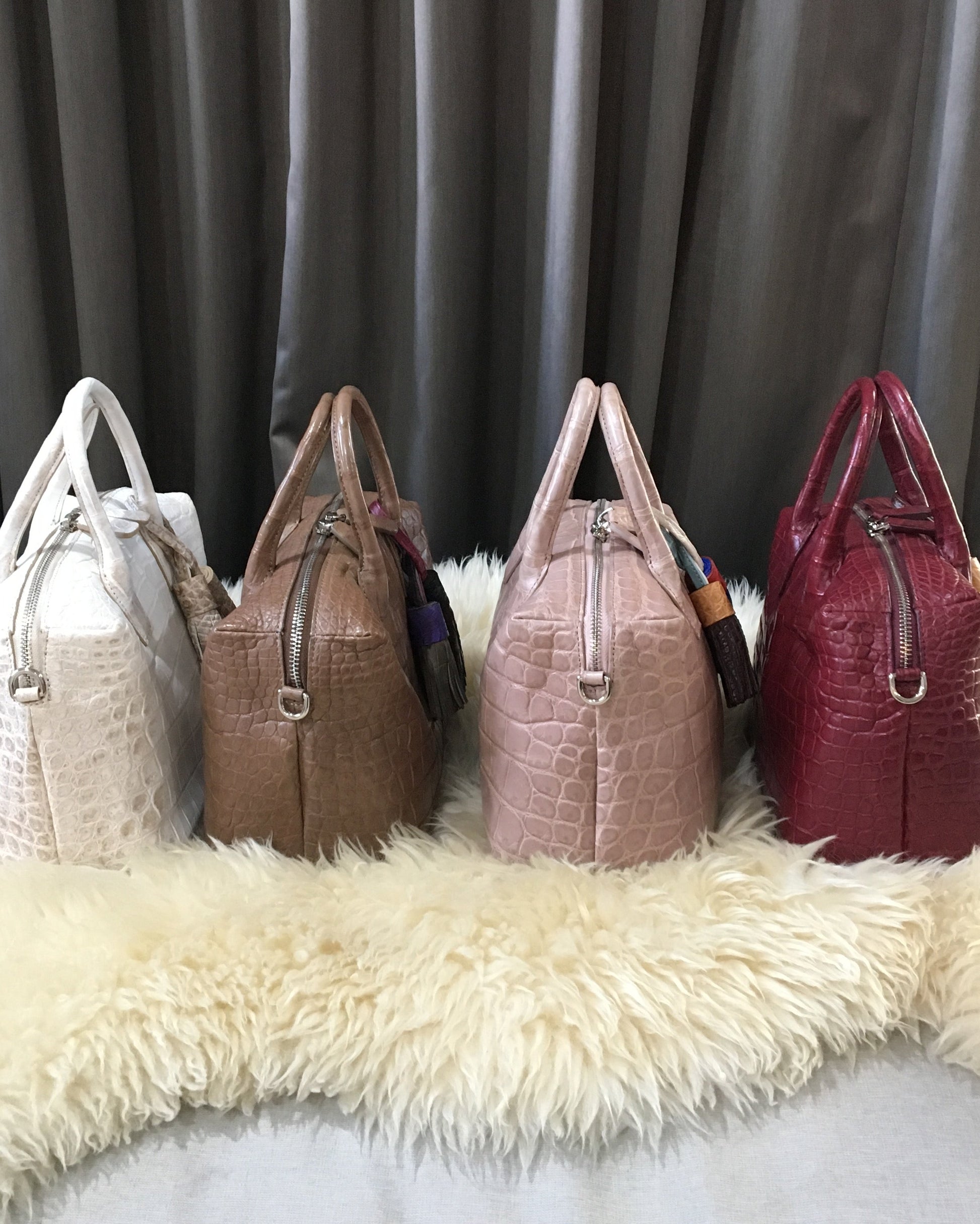Stack of handbags on a fur surface with a gray curtain background