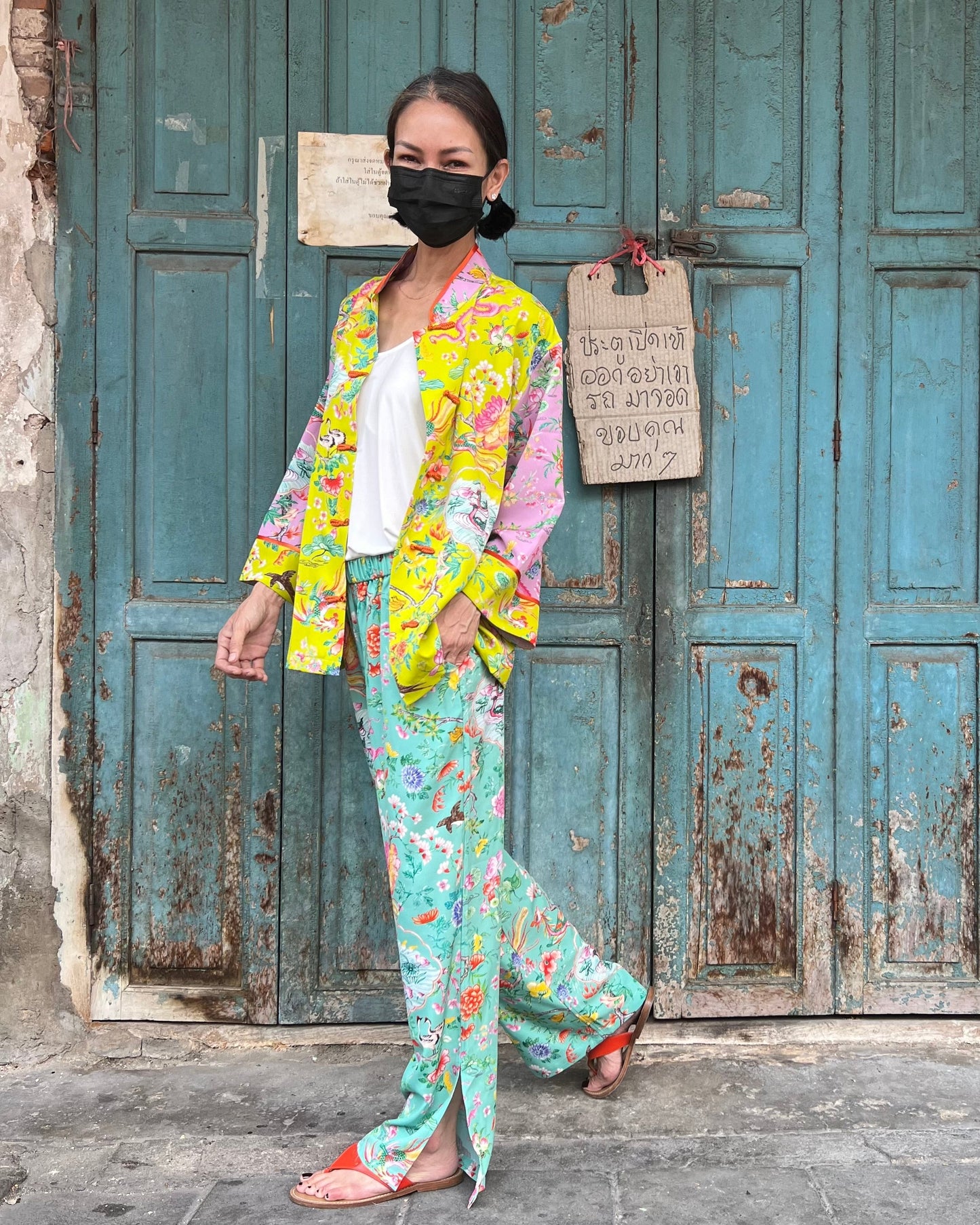Woman in colorful outfit standing in front of a rustic blue door.