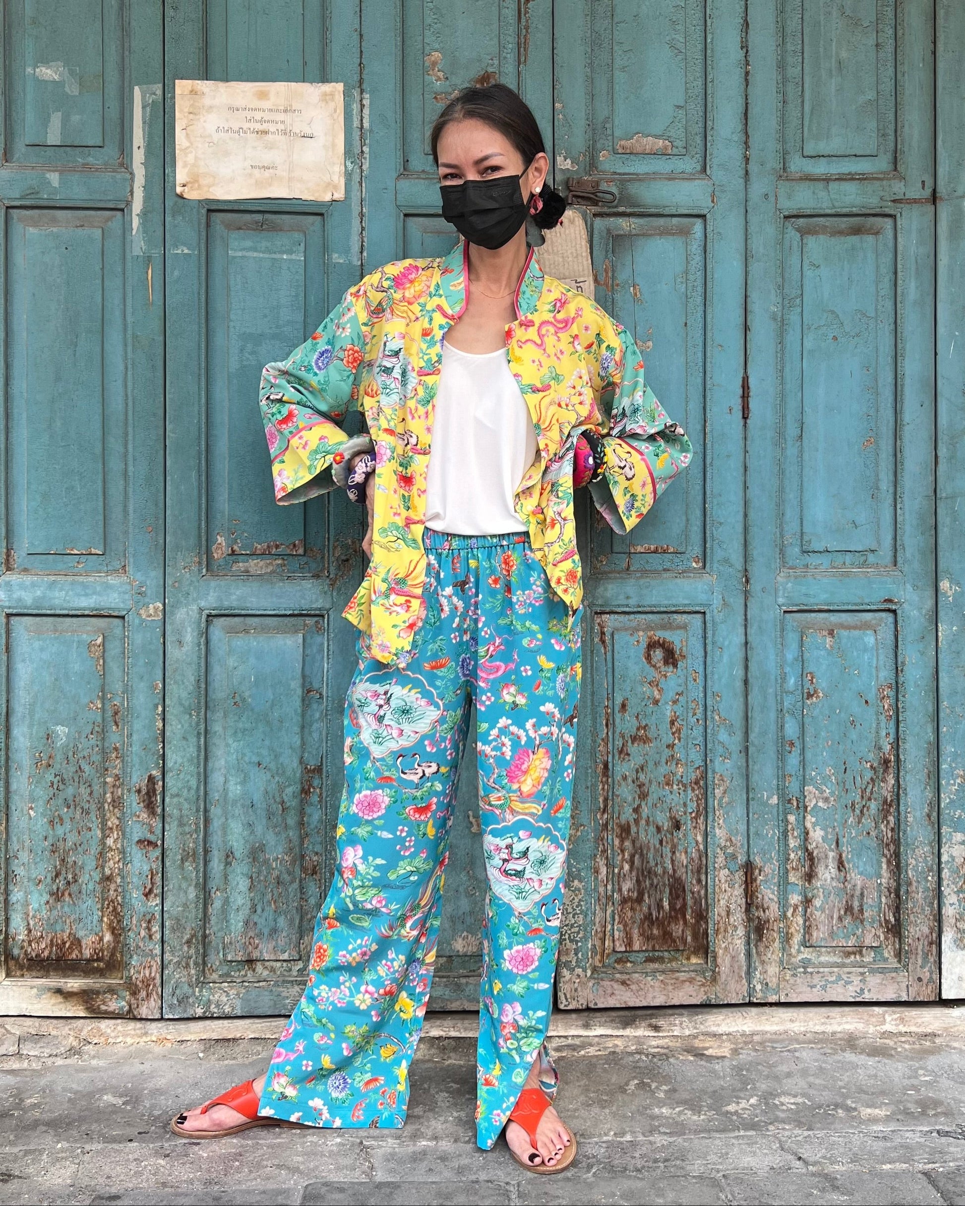 Person wearing a colorful outfit in front of a weathered blue door.