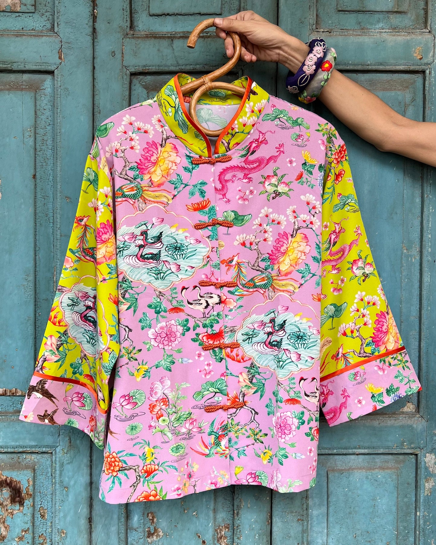 Colorful floral-patterned dress on a hanger against a rustic blue wooden door.