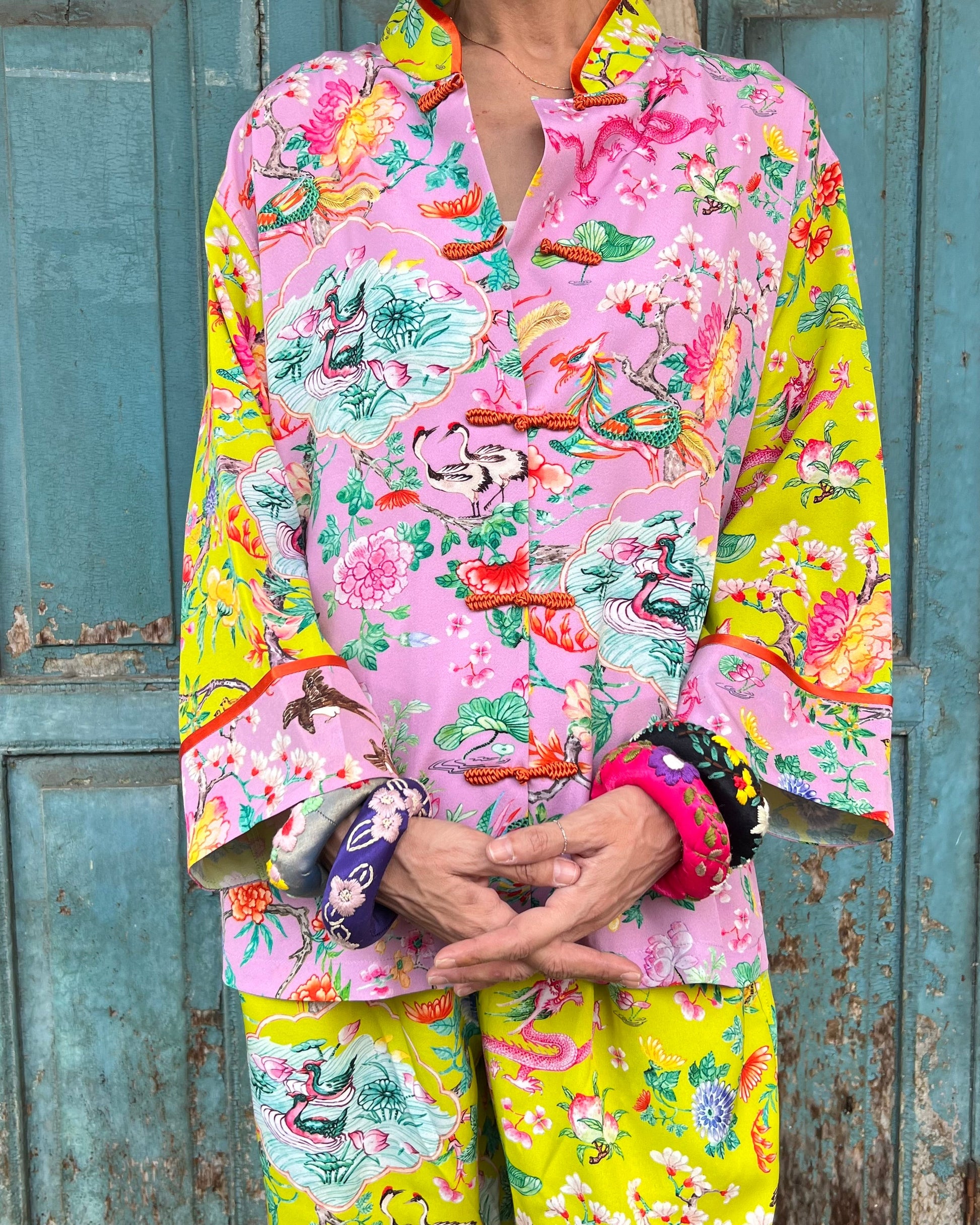Person wearing a colorful floral outfit in front of a blue wooden door.