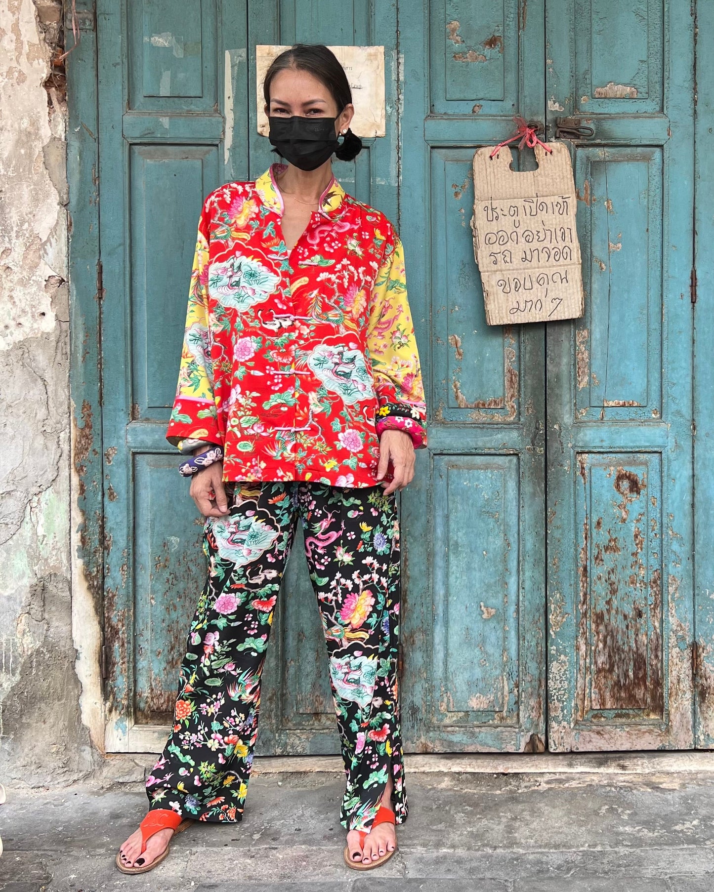 Person wearing a colorful outfit in front of a weathered blue door.