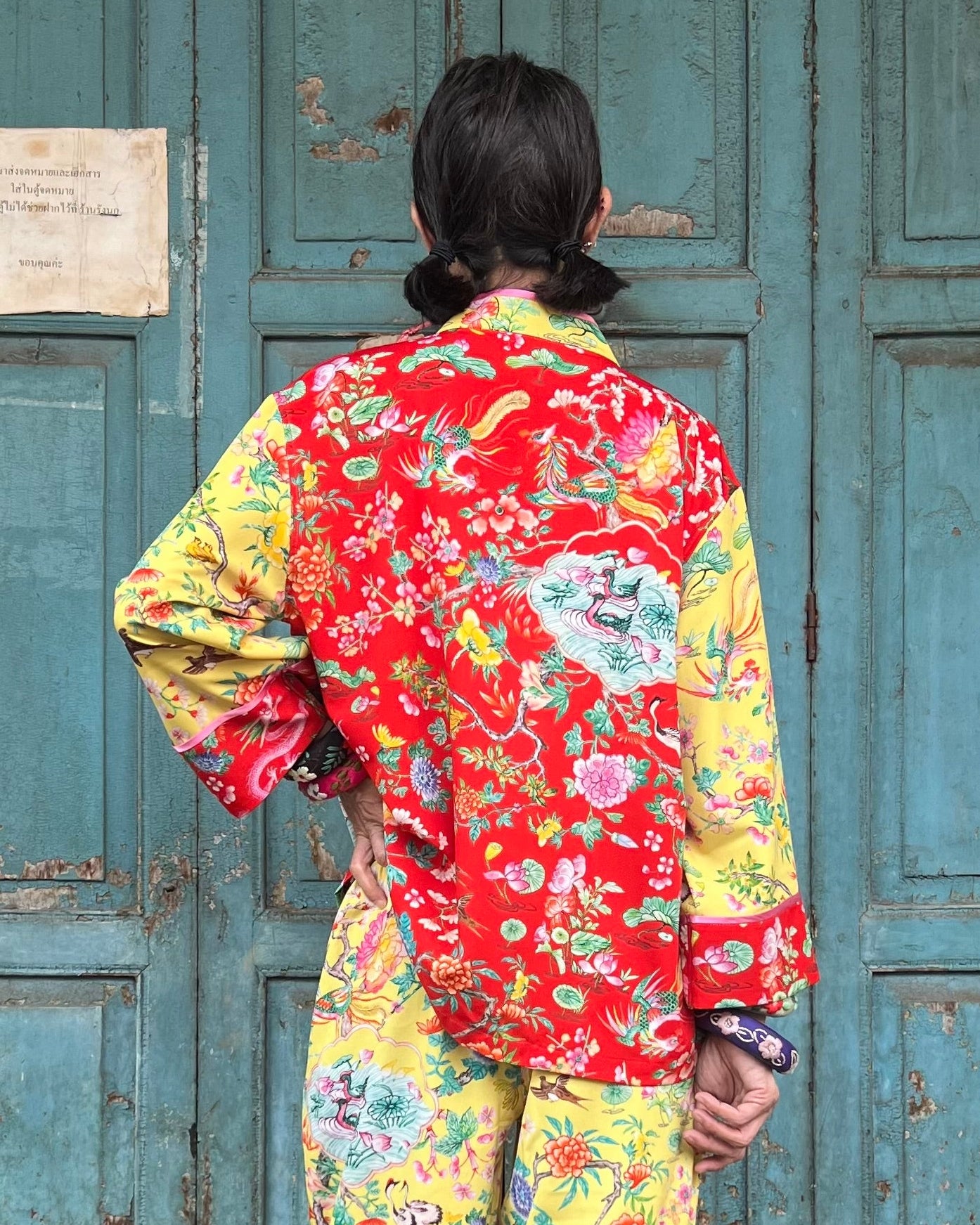 Person wearing a colorful floral jacket in front of a blue door