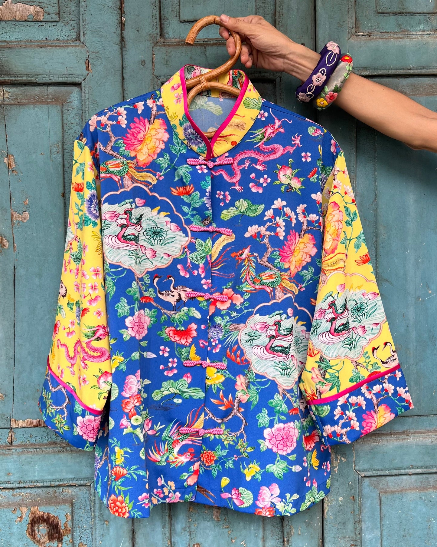 Colorful traditional patterned shirt on a hanger against a rustic wooden door background