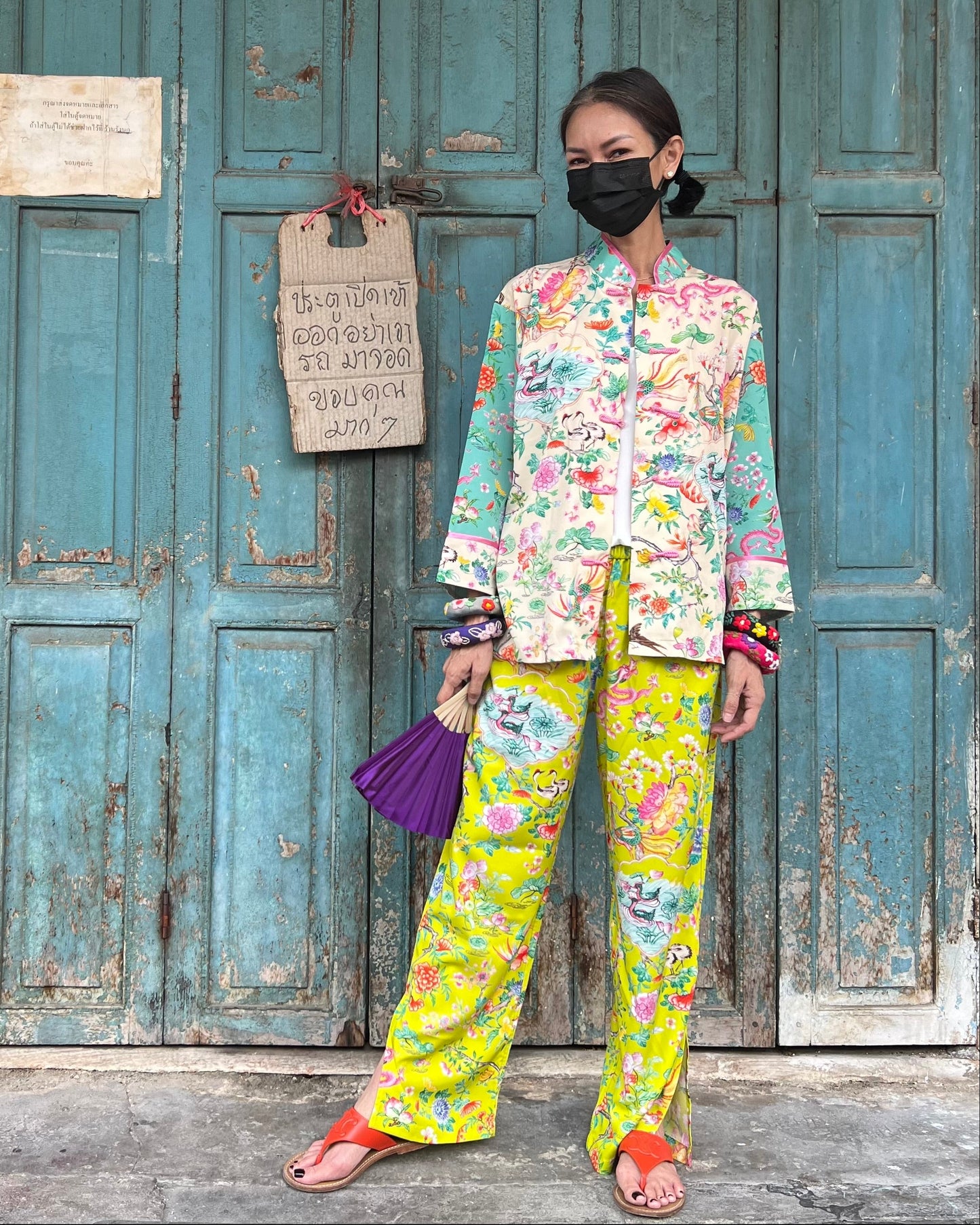Woman in colorful outfit standing in front of a rustic wooden door.