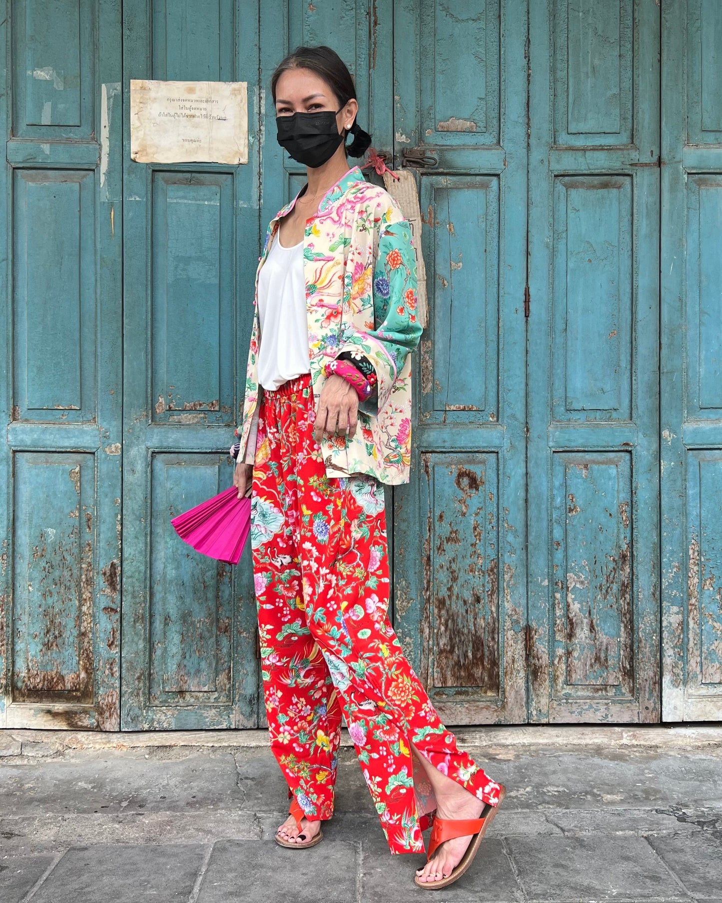 Woman in colorful outfit standing in front of a weathered blue door.