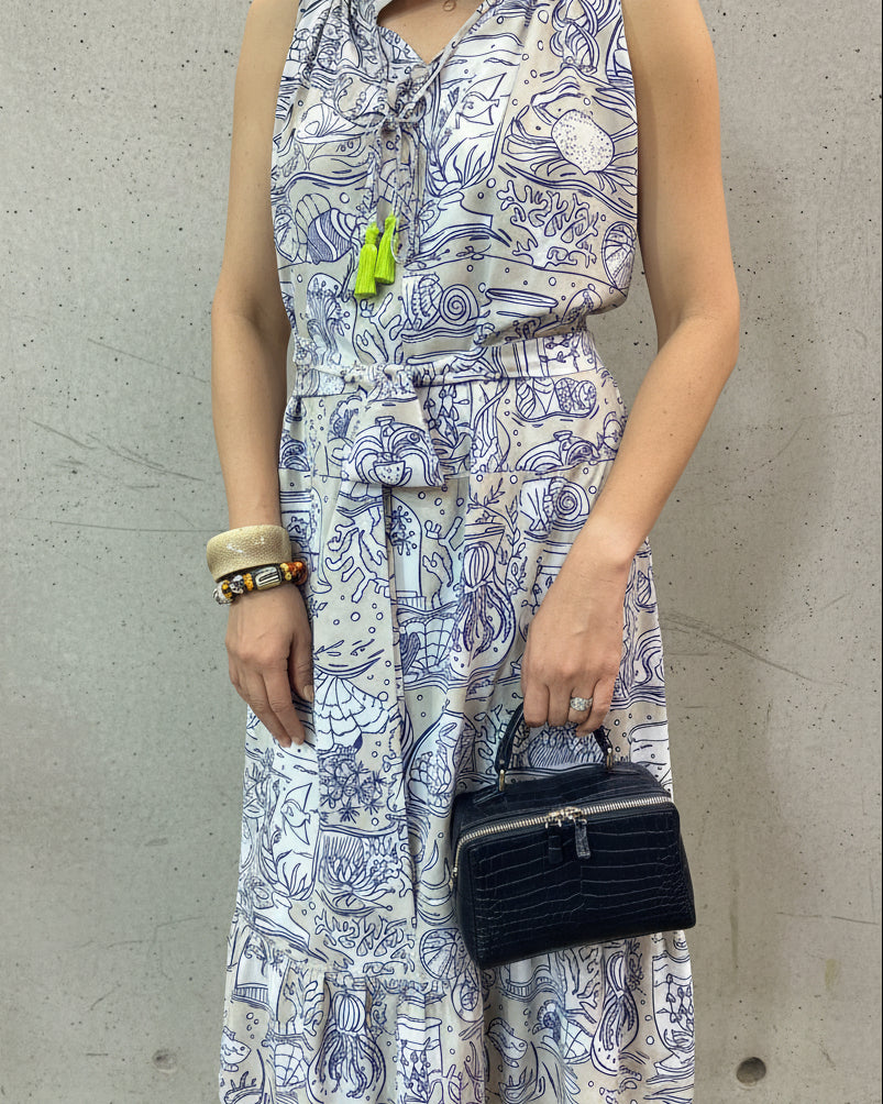 Person wearing a patterned dress holding a black handbag 