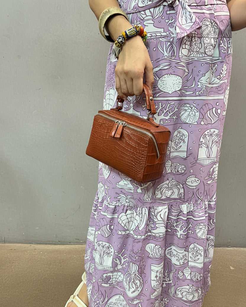 Person holding a brown leather wallet over a patterned fabric surface