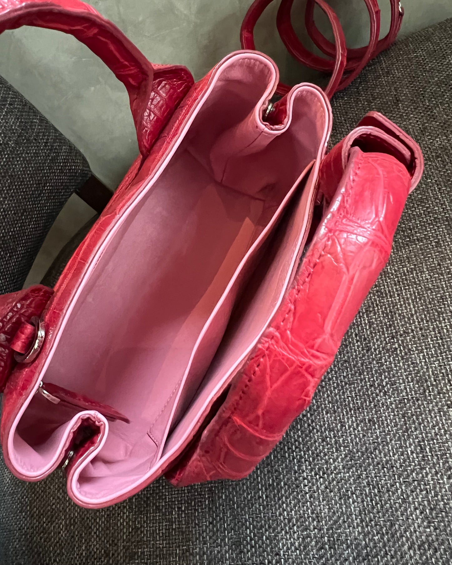 Red/pink handbag with a textured surface on a gray background
