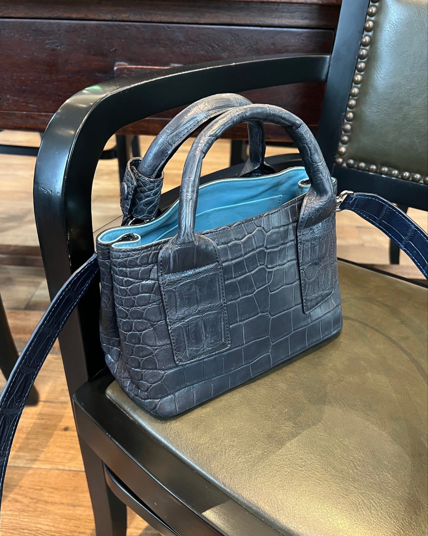 Black textured handbag on a wooden chair