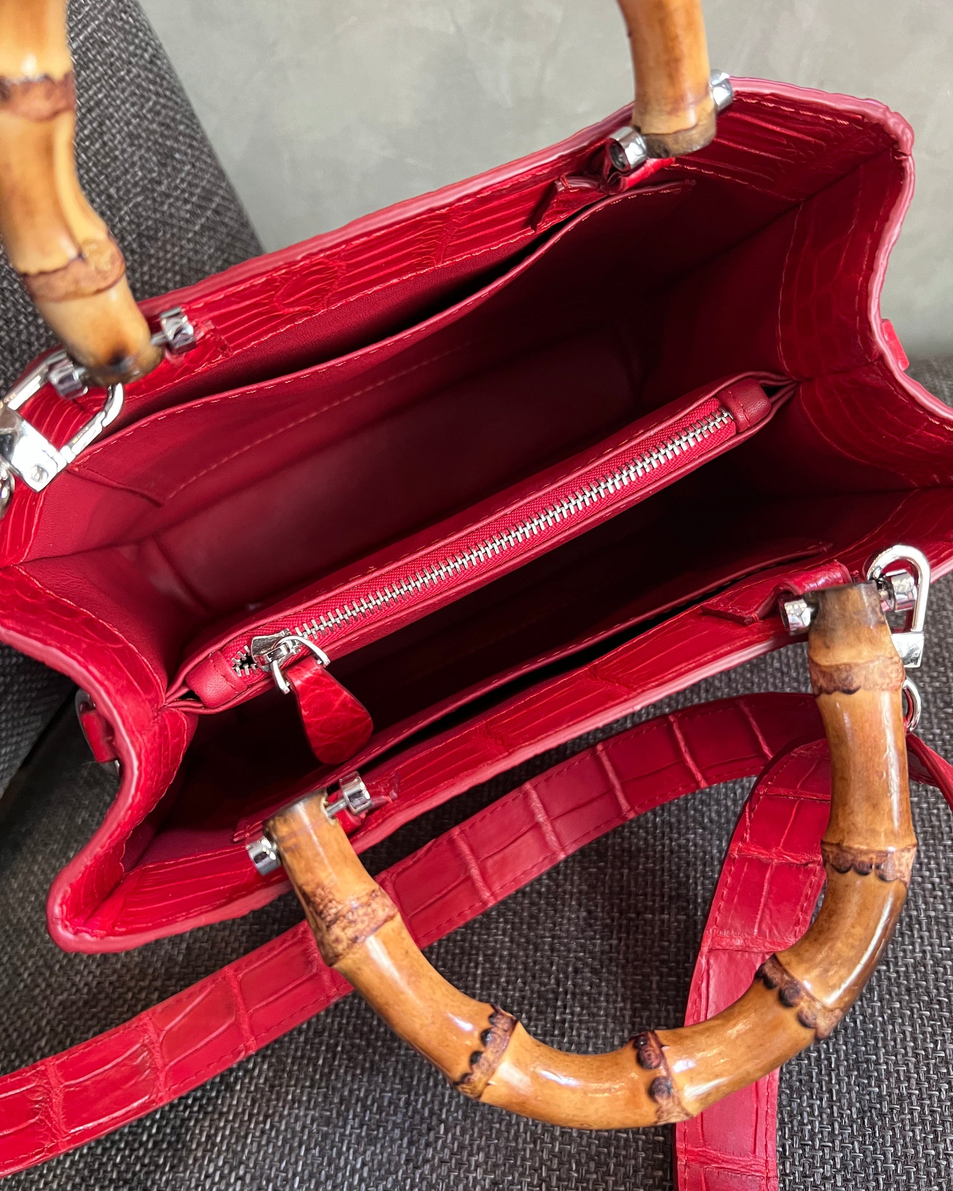 Red handbag with bamboo handles on a textured surface