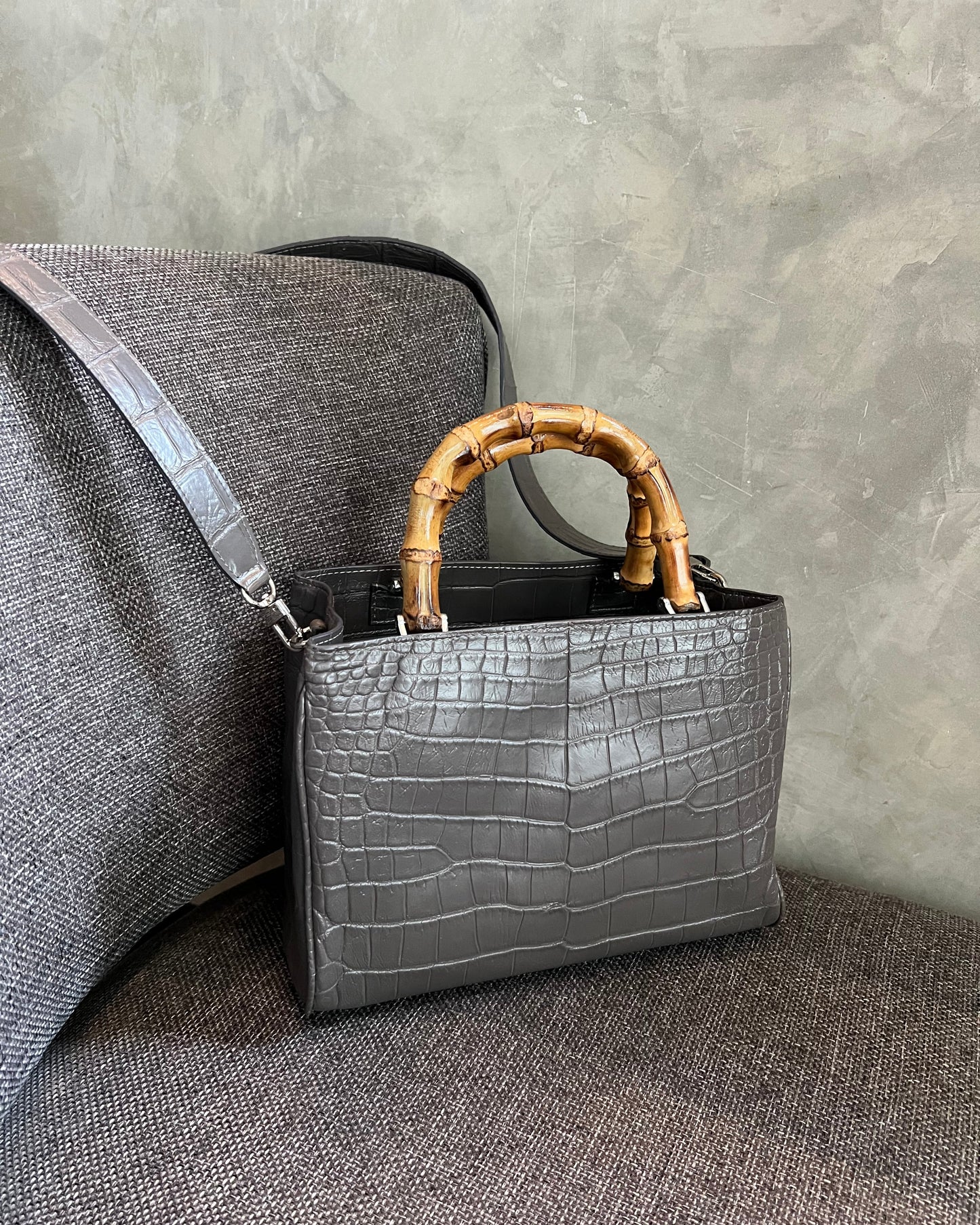 Gray handbag with bamboo handle on a gray surface