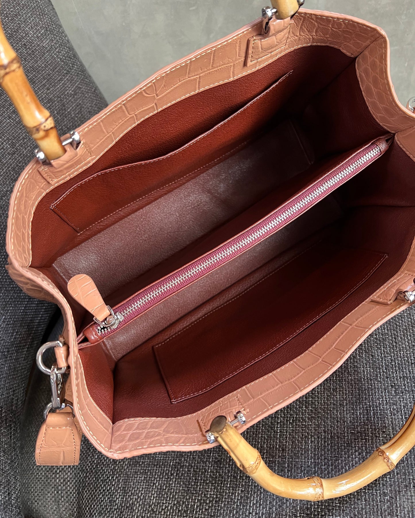 Brown leather handbag with bamboo handles on a gray surface