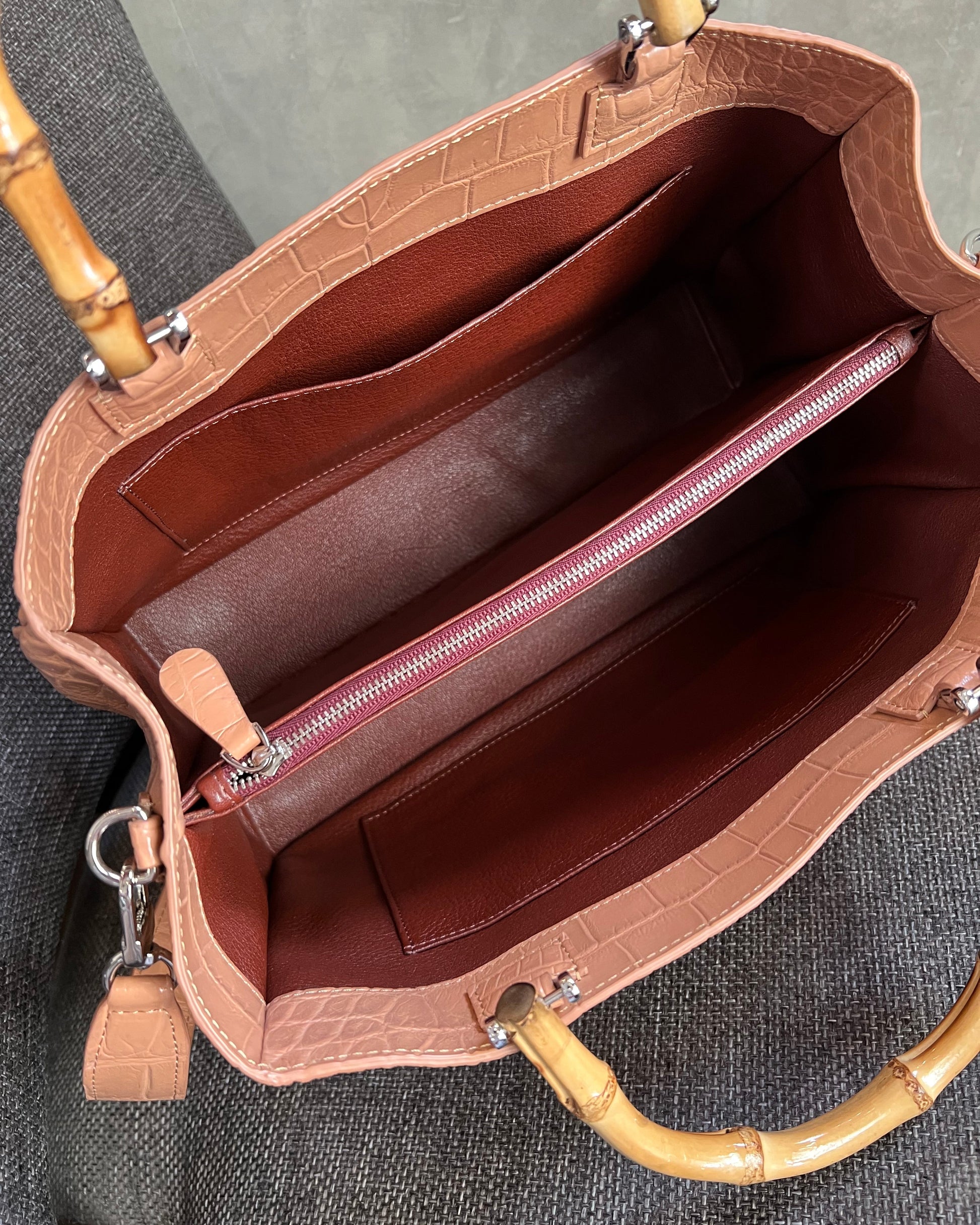 Brown leather handbag with bamboo handles on a gray surface