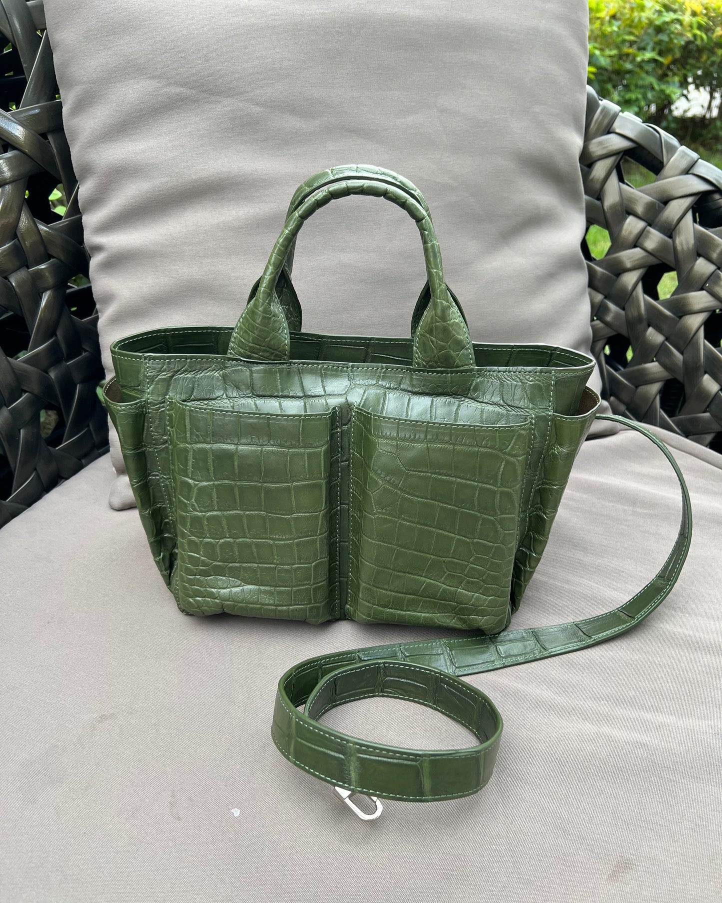 Green crocodile-patterned handbag on a light gray surface