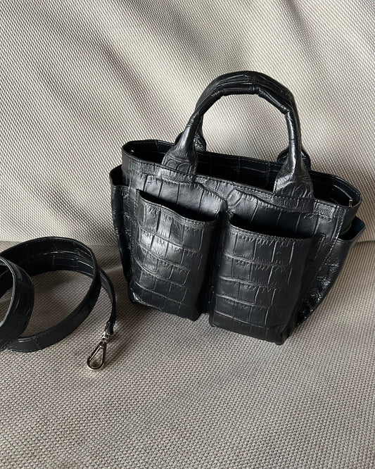 Black crocodile-patterned handbag with a detachable strap on a light gray background