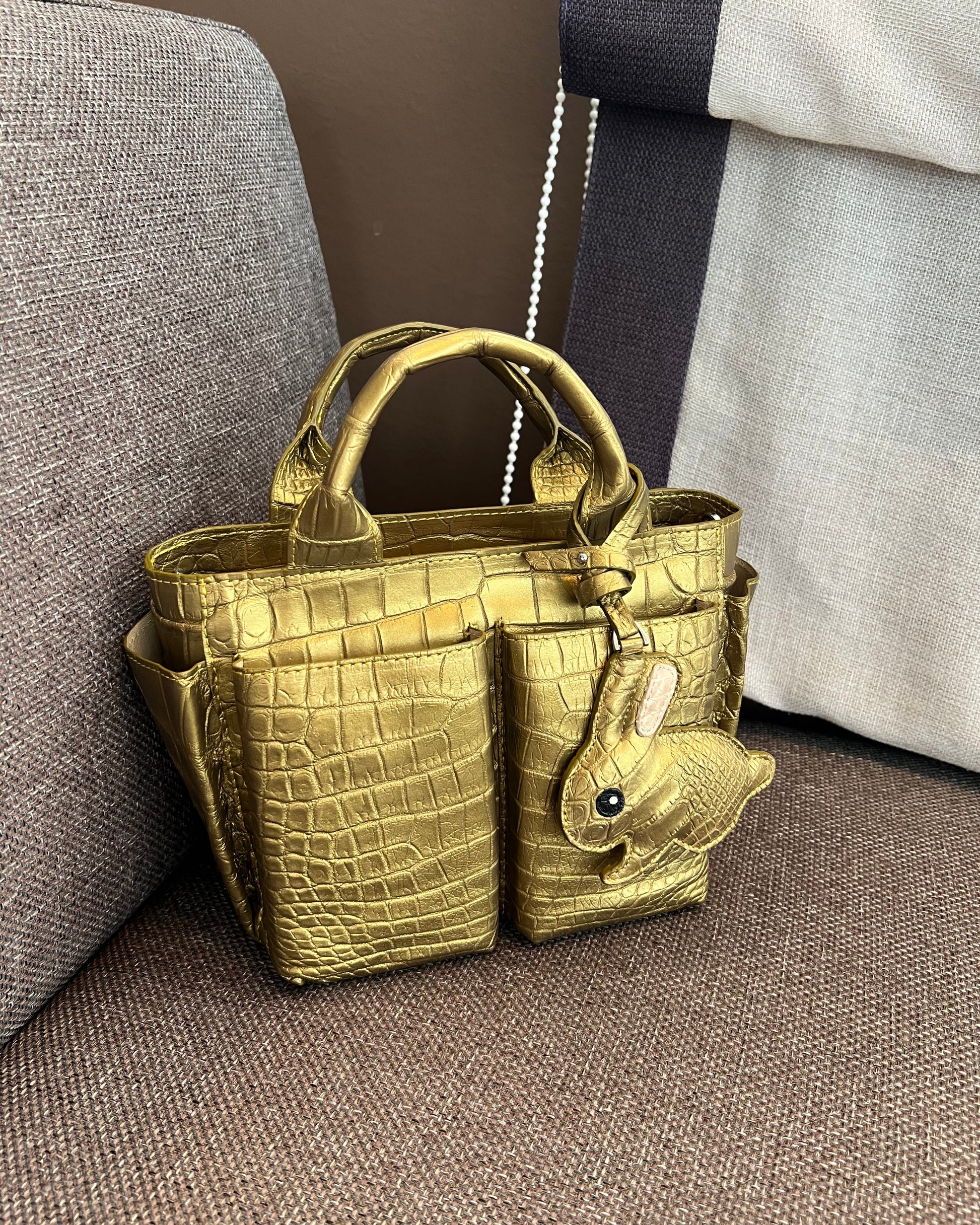 Gold crocodile-patterned handbag on a gray surface