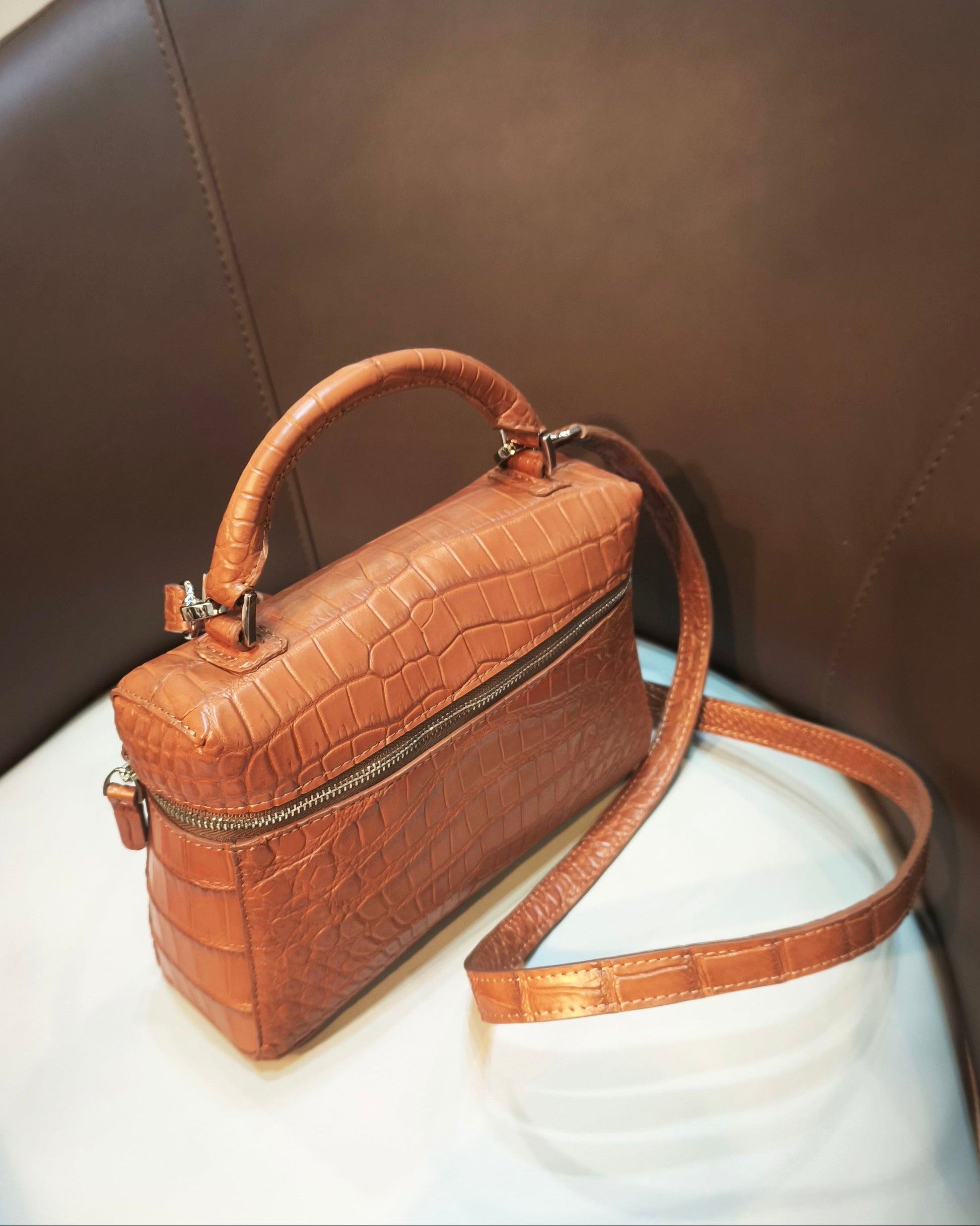 Brown crocodile-patterned handbag on a chair