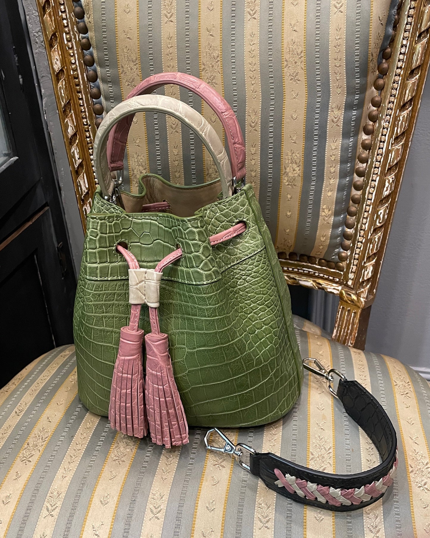 Green handbag with pink tassels on a striped chair