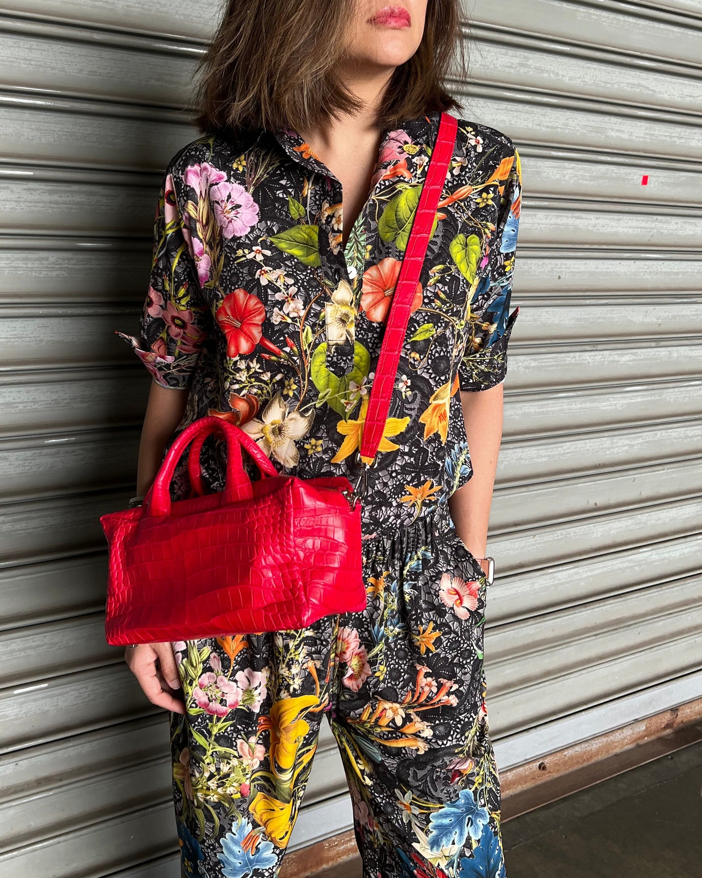 Person wearing a floral dress with red accents on a striped floor.