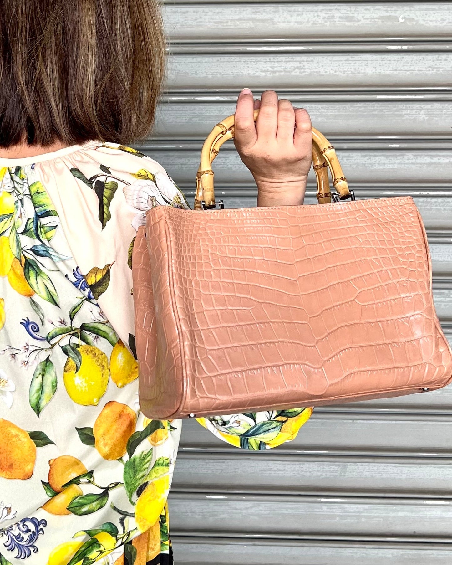 Person holding a beige textured handbag with a blurred background