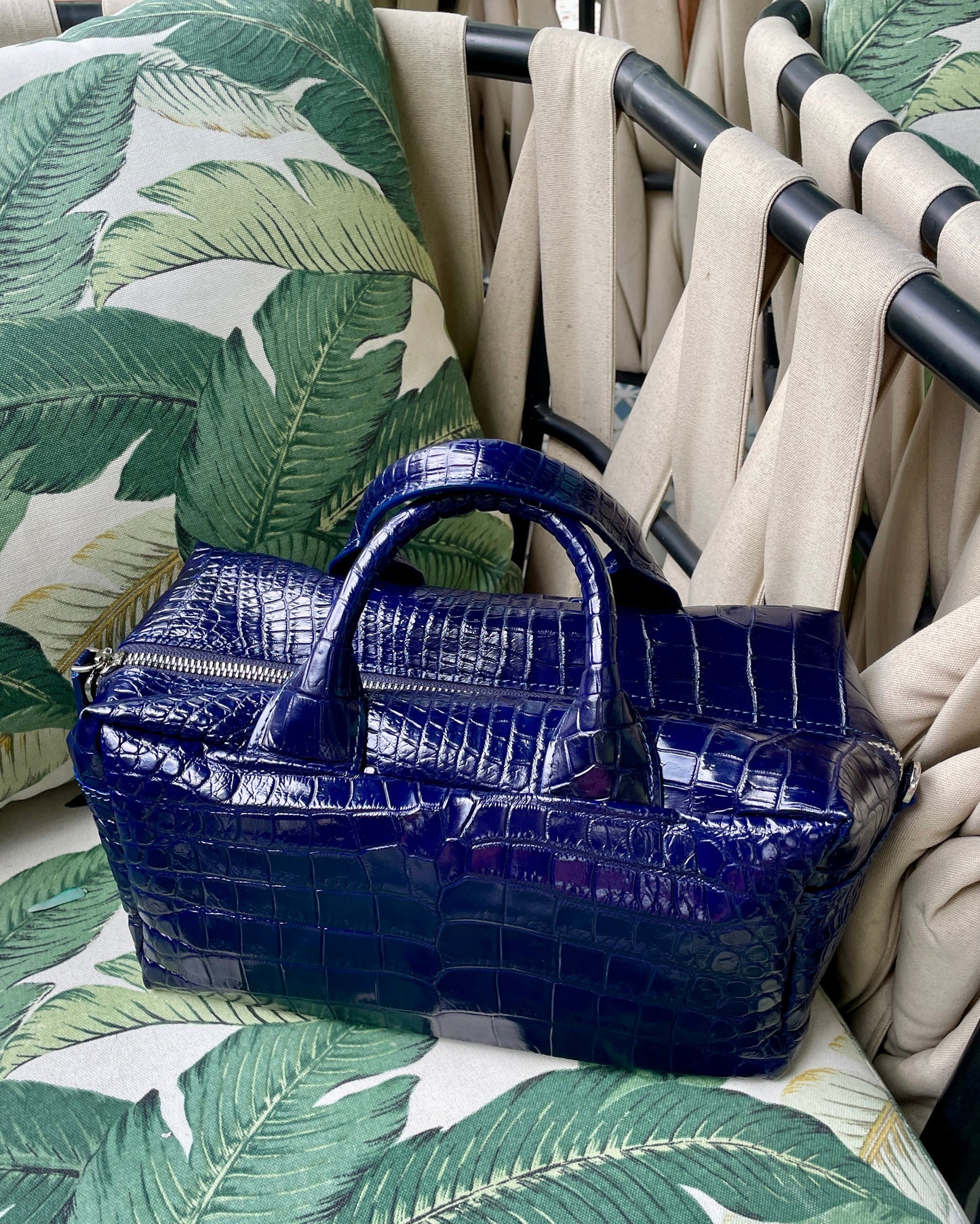 Blue textured handbag on a chair with leaf-patterned cushions