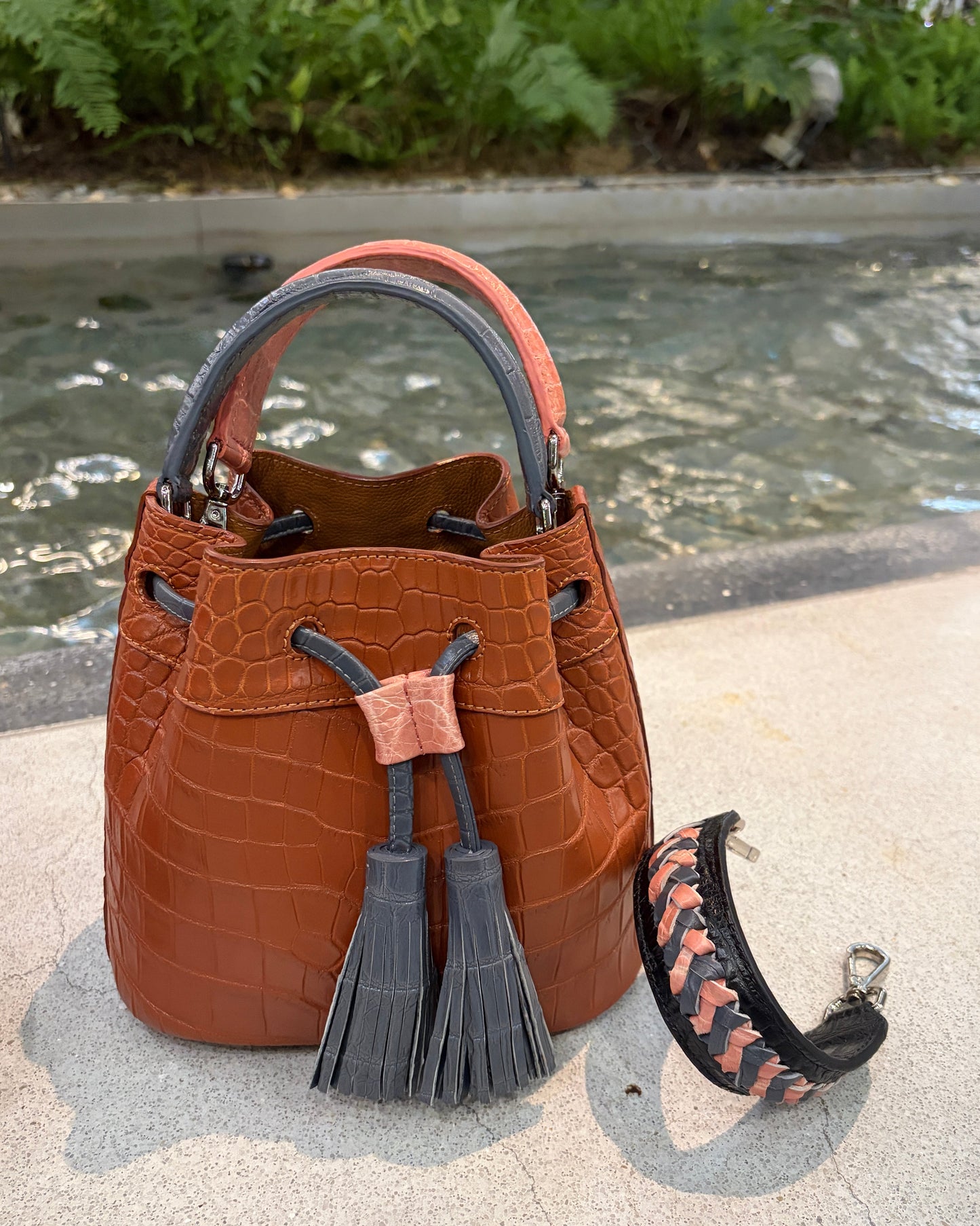 Brown leather handbag with a decorative tassel on a textured surface