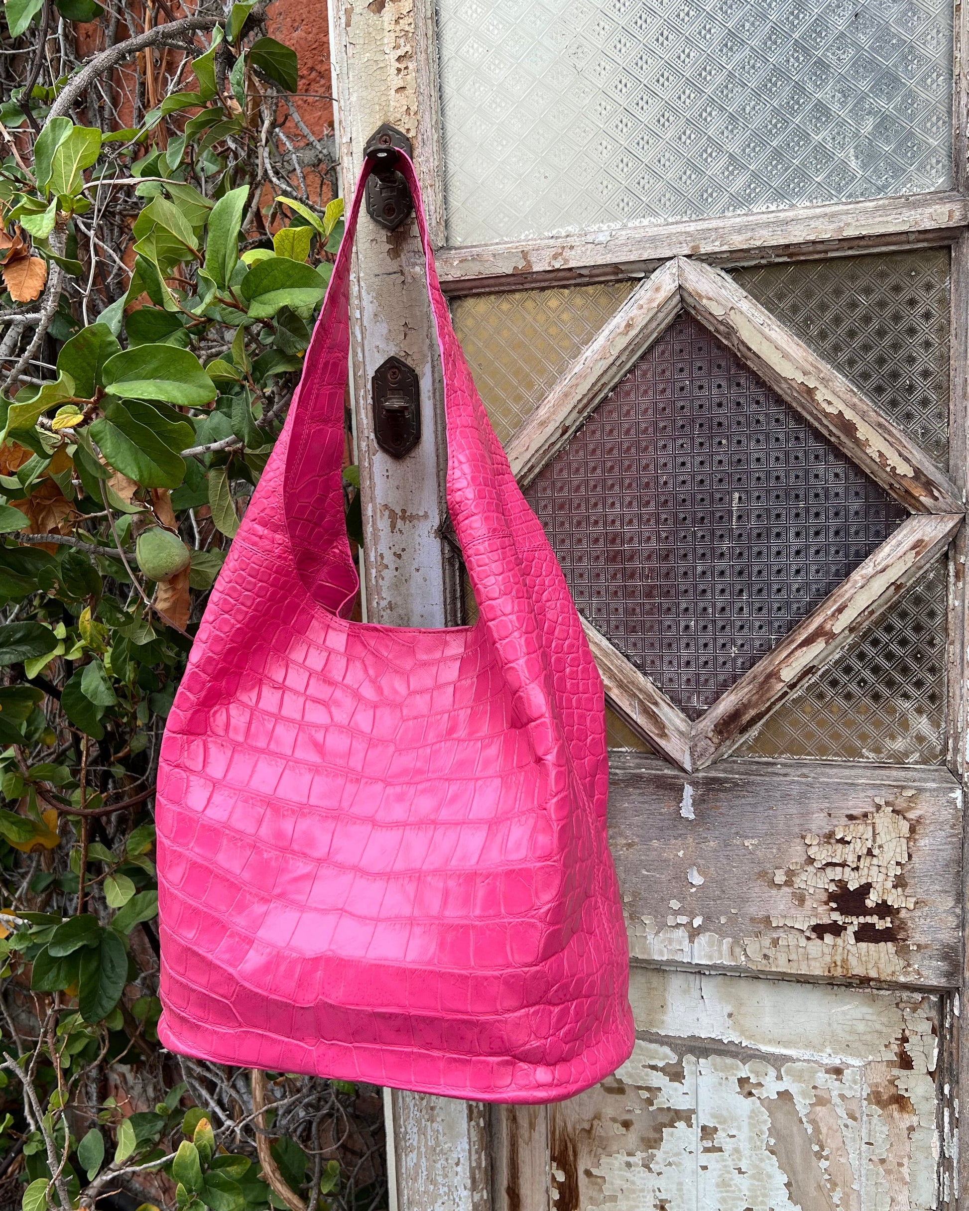 Pink textured bag hung over a wooden surface with a rustic background