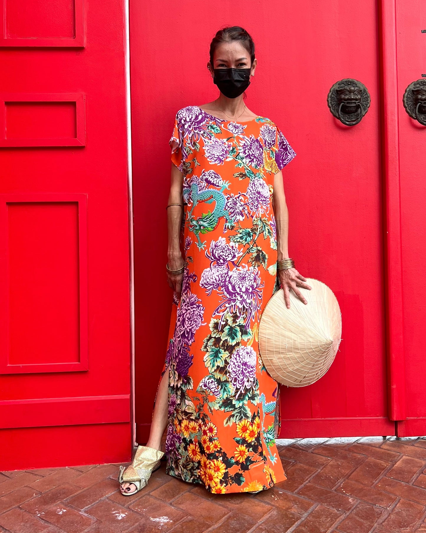 Woman in a colorful floral dress standing in front of a red door