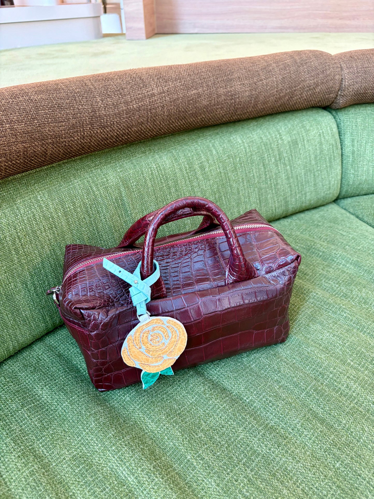 Brown leather bag with a decorative tag on a green couch
