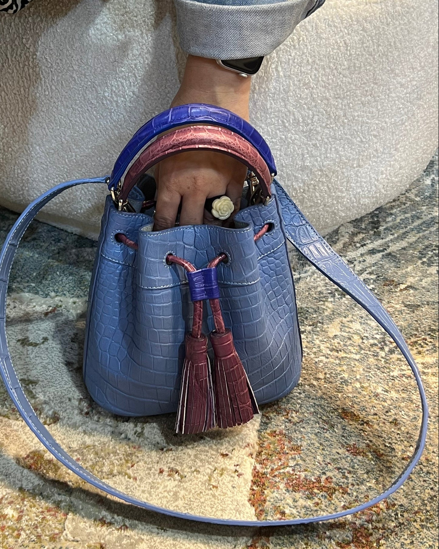 Person sitting on a stone surface with a blue handbag open in front of them.
