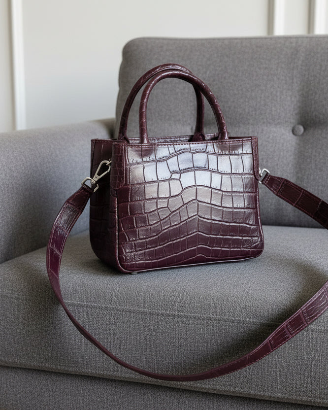 Brown crocodile-patterned handbag on a striped fabric background