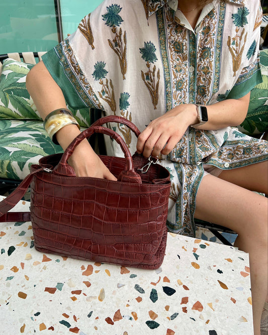 Person holding a brown handbag on a terrazzo-patterned floor.