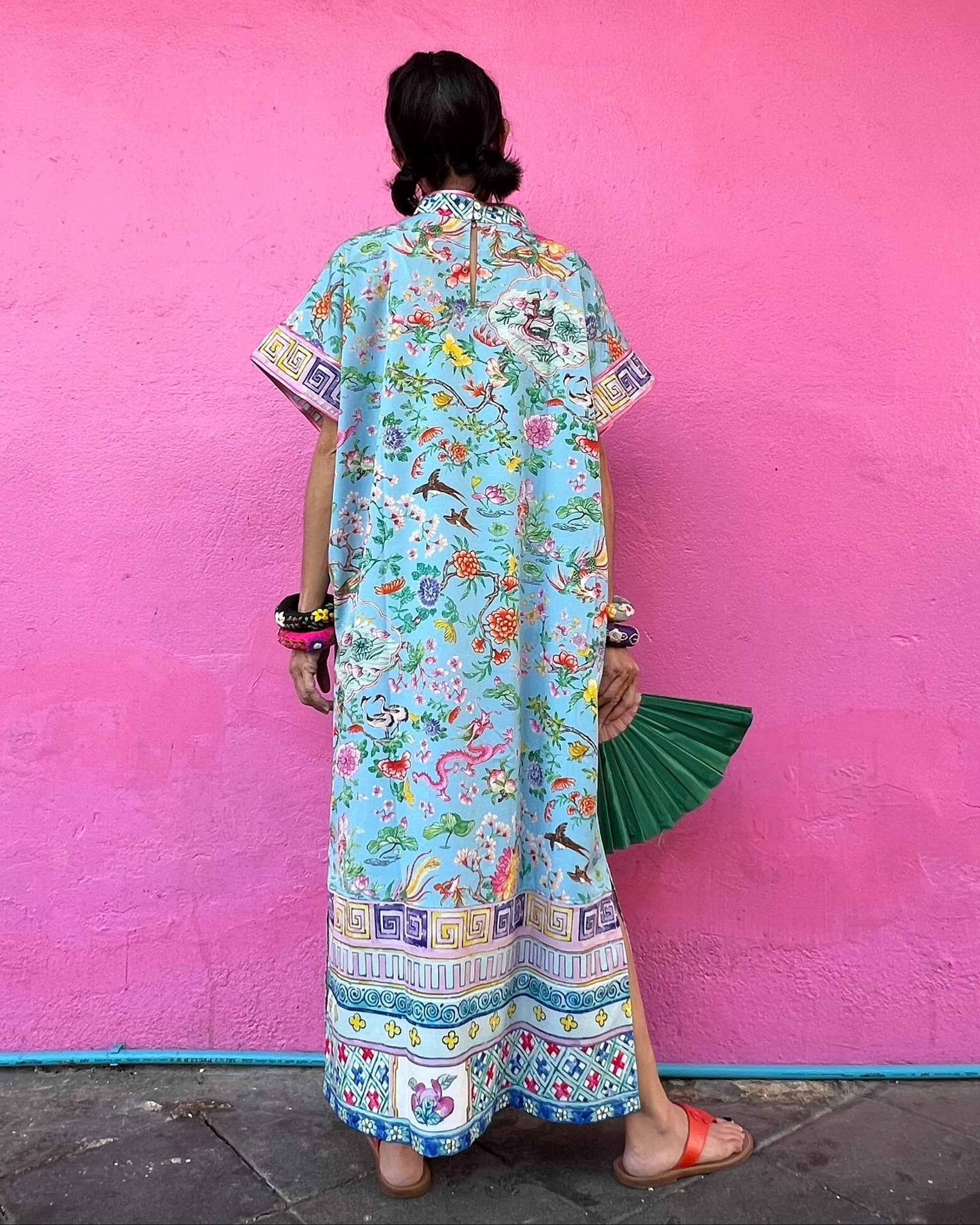 Person wearing a colorful dress against a pink wall