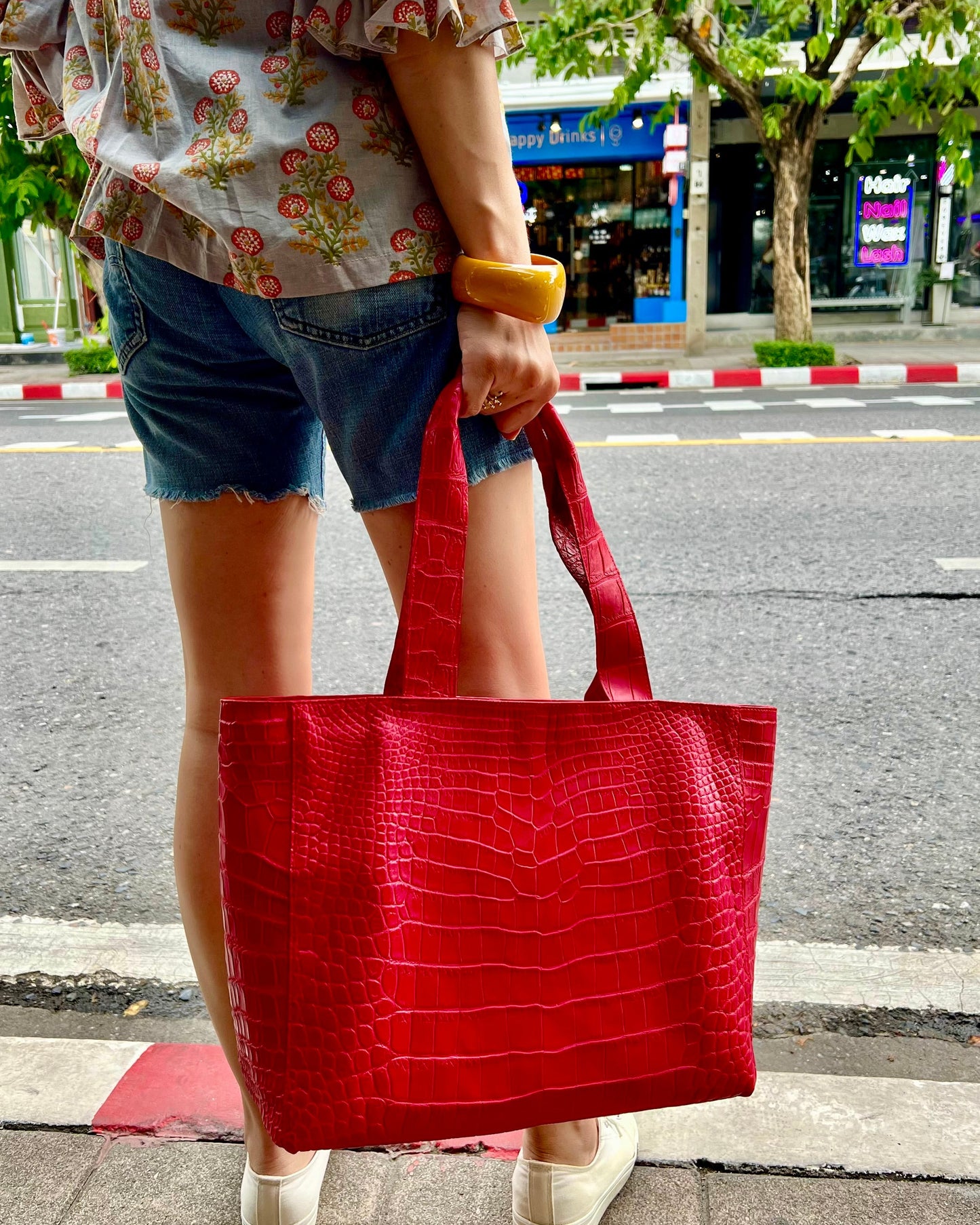Person holding a red textured handbag on a city street