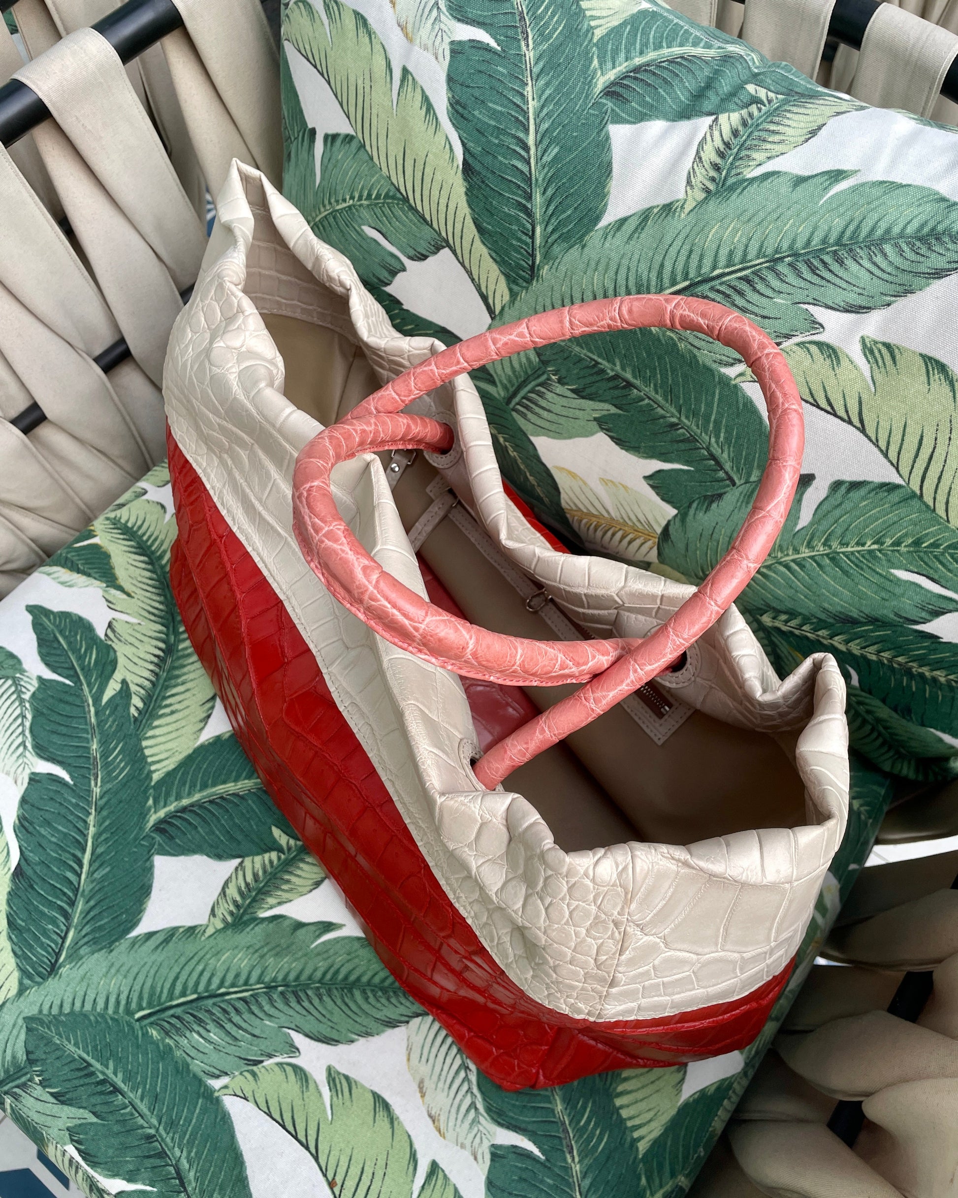 Red and white bag with a pink handle on a green leaf-patterned surface