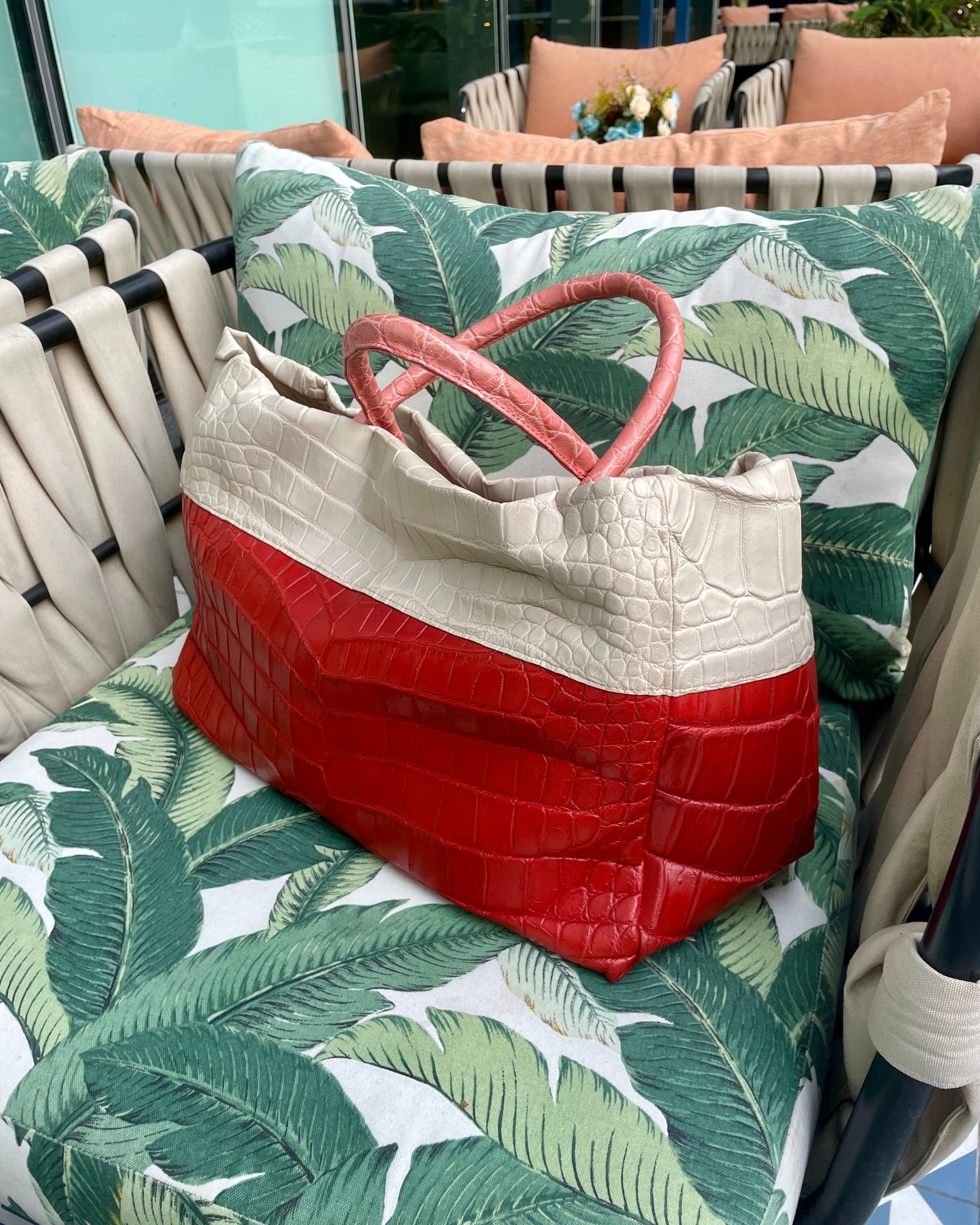 Red and white bag on a green leaf-patterned chair outdoors