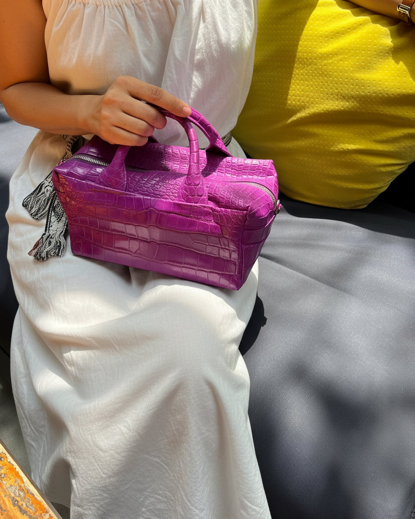Person holding a purple bag with floral-patterned fabric underneath