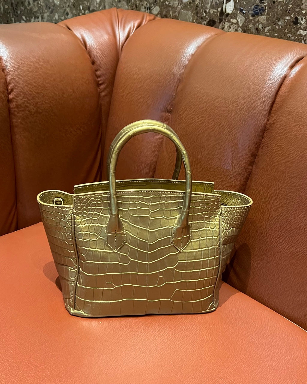 Gold textured handbag on a brown leather couch