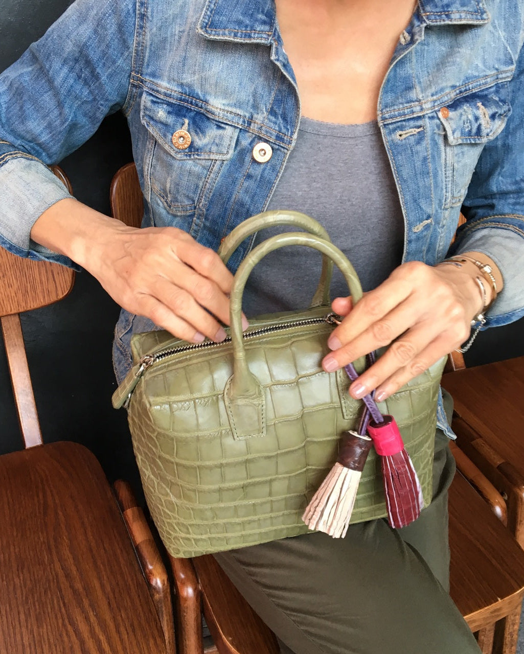 Person holding a green handbag with a keychain in an indoor setting